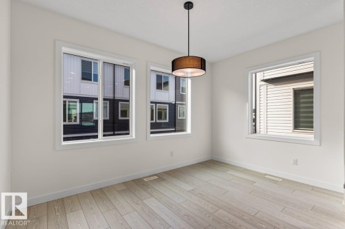 This room features light-colored plank flooring, white walls, and bright white trim around the windows - 42 Corner Glen Manor Ne, Calgary, AB - Indoor Photo Showing Other Room