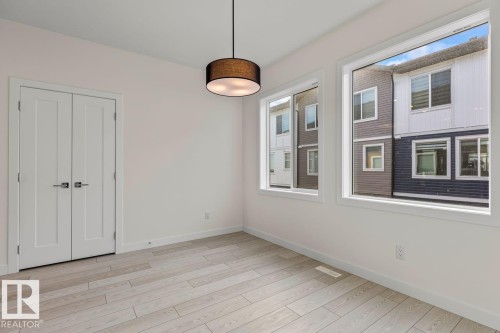 The room features light-colored plank flooring, white walls, and a modern drum pendant light fixture - 42 Corner Glen Manor Ne, Calgary, AB - Indoor Photo Showing Other Room