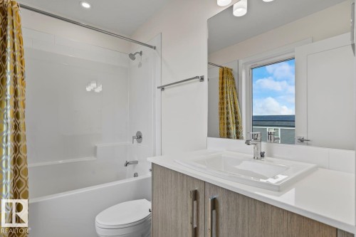 Bathroom featuring a tub and shower combination with a bright shower curtain, a vanity with a rectangular sink, and a large mirror - 42 Corner Glen Manor Ne, Calgary, AB - Indoor Photo Showing Bathroom