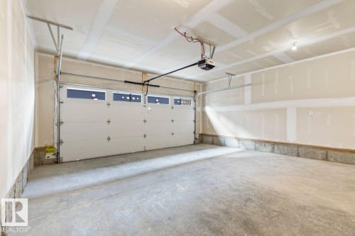 The property features a garage with a concrete floor and a white garage door with windows - 42 Corner Glen Manor Ne, Calgary, AB - Indoor Photo Showing Garage
