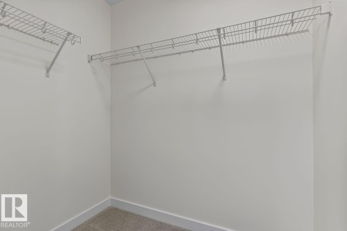 Walk-in closet featuring light gray walls, wire shelving, and carpeted flooring - 42 Corner Glen Manor Ne, Calgary, AB - Indoor With Storage