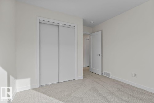 This room features light-colored walls, light carpet, and a closet with sliding doors - 42 Corner Glen Manor Ne, Calgary, AB - Indoor Photo Showing Other Room