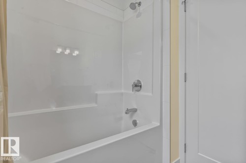 Bathroom featuring a white bathtub and shower combination with chrome fixtures - 42 Corner Glen Manor Ne, Calgary, AB - Indoor Photo Showing Bathroom