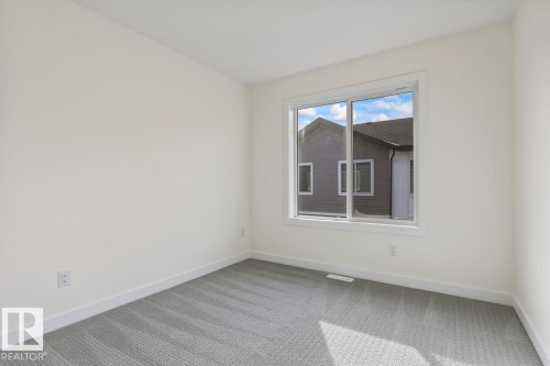 The room features light-colored walls, gray carpet, and a large window providing natural light - 42 Corner Glen Manor Ne, Calgary, AB - Indoor Photo Showing Other Room