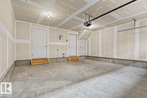 Spacious garage featuring a concrete floor, two entry doors with wooden steps, and an automatic garage door opener - 42 Corner Glen Manor Ne, Calgary, AB - Indoor