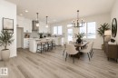 This open-concept living area features light-colored flooring, a modern kitchen with white cabinetry and a center island, and a dining area with a chandelier - 6298 180 Avenue, Edmonton, AB  - Indoor Photo Showing Other Room 