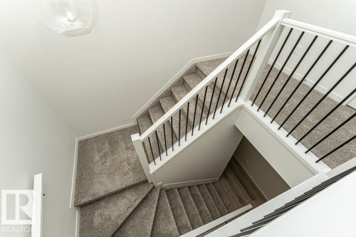 The property features a staircase with carpeted treads and risers, white handrails, and black balusters - 6298 180 Avenue, Edmonton, AB - Indoor Photo Showing Other Room