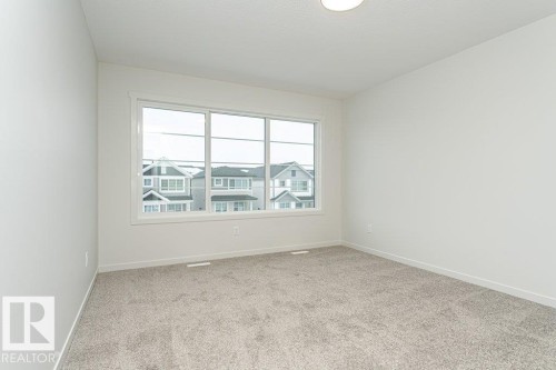 This room features light-colored walls, grey carpet flooring, and a window providing natural light - 6298 180 Avenue, Edmonton, AB - Indoor Photo Showing Other Room