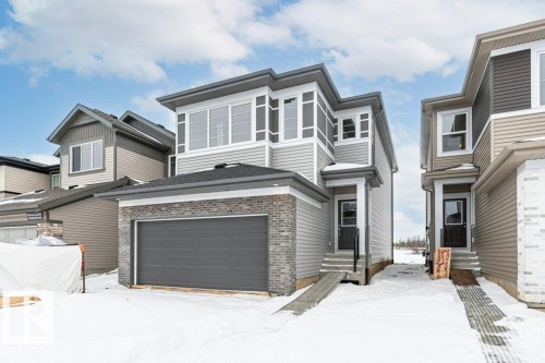 The property features an attached garage with a dark gray door, light gray brick detailing, and complementary gray siding - 6298 180 Avenue, Edmonton, AB - Outdoor With Facade