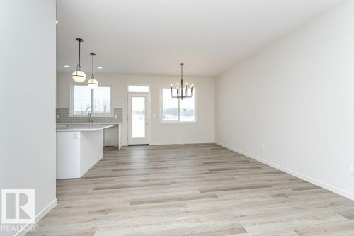 Open concept living area with light-toned flooring, white walls, and contemporary light fixtures - 6298 180 Avenue, Edmonton, AB - Indoor