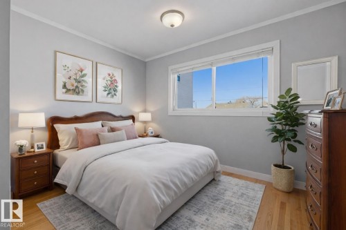 This room features hardwood floors, light gray walls, and a large window providing ample natural light - 10612 79 Street, Edmonton, AB - Indoor Photo Showing Bedroom