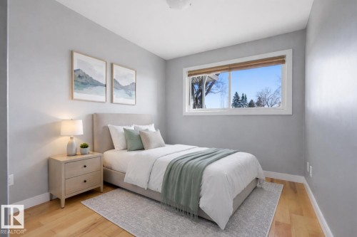 This room features light hardwood flooring and a large window providing views of the exterior - 10612 79 Street, Edmonton, AB - Indoor Photo Showing Bedroom