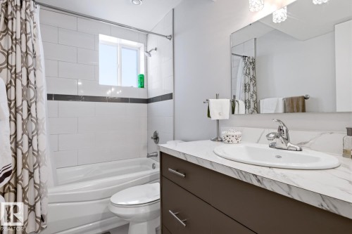 Bathroom featuring a vanity with a white countertop and an integrated sink, a mirror, and a bathtub with white subway tile surround - 10612 79 Street, Edmonton, AB - Indoor Photo Showing Bathroom