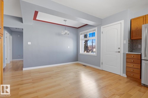 This bright space features light wood flooring, a window offering views of the outdoors, and a contemporary ceiling light fixture - 10612 79 Street, Edmonton, AB - Indoor Photo Showing Other Room