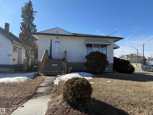 The property features a white exterior with a dark roof, a front porch with wooden steps, and a concrete pathway leading to the entrance - 10849 73 Avenue, Edmonton, AB - Outdoor