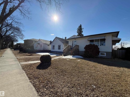 This property features a front yard with a lawn, a small shrub, and a concrete sidewalk - 10835/39/45/49 73 Avenue, Edmonton, AB 