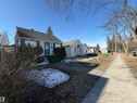 The property features an exterior with light-colored siding, a dark-colored roof, and a green front door - 10835/39/45/49 73 Avenue, Edmonton, AB 