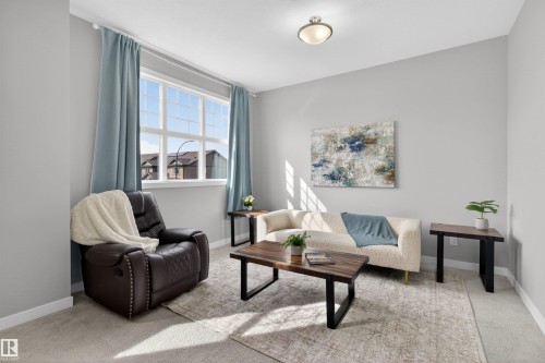 This living area features a large window with light blue curtains, light grey walls, and a ceiling light fixture - 42 Prescott Boulevard, Spruce Grove, AB - Indoor Photo Showing Living Room