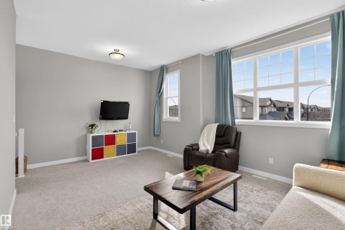 Living area featuring carpeted flooring, light grey walls, and large windows providing natural light - 42 Prescott Boulevard, Spruce Grove, AB - Indoor Photo Showing Living Room
