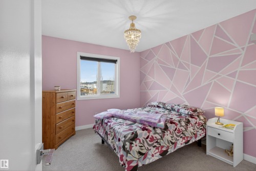 The room features a window with a view, a light fixture, and walls with a geometric pattern - 42 Prescott Boulevard, Spruce Grove, AB - Indoor Photo Showing Bedroom