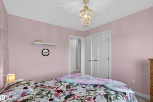 This room features light pink walls, a decorative ceiling light fixture, and white doors - 42 Prescott Boulevard, Spruce Grove, AB - Indoor Photo Showing Bedroom