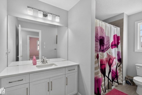 The bathroom features a vanity with a white countertop and a rectangular sink, complemented by a large wall-mounted mirror - 42 Prescott Boulevard, Spruce Grove, AB - Indoor Photo Showing Bathroom