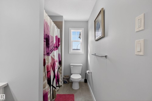 Bathroom with light gray walls, a window providing natural light, a toilet, and light-colored floor tiles - 42 Prescott Boulevard, Spruce Grove, AB - Indoor Photo Showing Bathroom