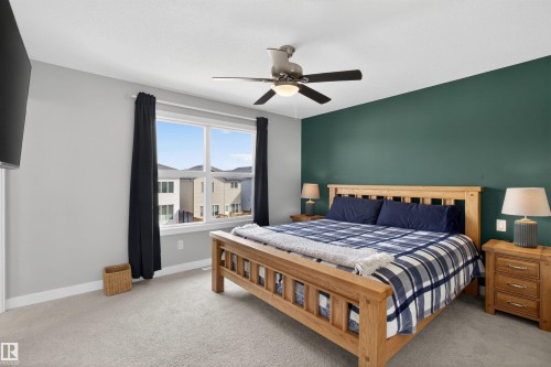 This bedroom features carpeted flooring, a ceiling fan with integrated lighting, and a window with black curtains providing natural light - 42 Prescott Boulevard, Spruce Grove, AB - Indoor Photo Showing Bedroom