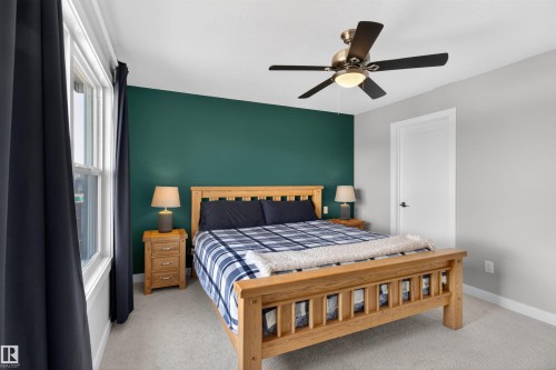 This bedroom features a vibrant accent wall, a ceiling fan with integrated lighting, and light-colored carpeting - 42 Prescott Boulevard, Spruce Grove, AB - Indoor Photo Showing Bedroom
