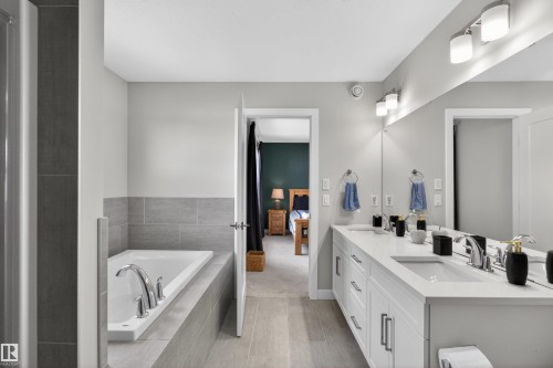 Well-appointed bathroom featuring a double vanity with ample counter space and two sinks, a built-in bathtub, and tiled flooring - 42 Prescott Boulevard, Spruce Grove, AB - Indoor Photo Showing Bathroom
