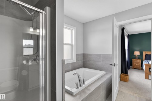 Bathroom featuring a tiled shower enclosure, a built-in bathtub with a window, and light grey tile flooring - 42 Prescott Boulevard, Spruce Grove, AB - Indoor Photo Showing Bathroom