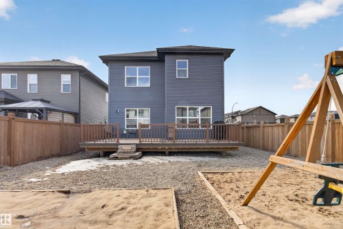 The property features a dark-toned exterior with multiple windows and a private wooden deck - 42 Prescott Boulevard, Spruce Grove, AB - Outdoor With Deck Patio Veranda