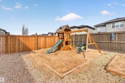 The property features a fenced backyard with a sand play area and a wooden playset, complete with a slide and swings - 42 Prescott Boulevard, Spruce Grove, AB - Outdoor
