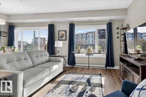 Living area featuring light wood flooring, large windows, and a view of the surrounding buildings - 214 528 Griesbach Parade Parade, Edmonton, AB - Indoor Photo Showing Living Room