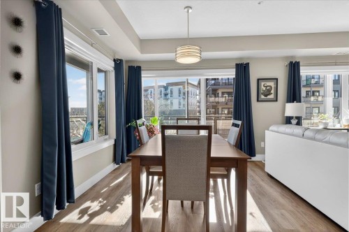 The dining area features engineered wood flooring and expansive windows, allowing natural light to fill the space - 214 528 Griesbach Parade Parade, Edmonton, AB - Indoor Photo Showing Dining Room