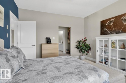 This room features light-colored walls and carpeting, with a contrasting accent wall in a dark blue hue - 214 528 Griesbach Parade Parade, Edmonton, AB - Indoor Photo Showing Bedroom