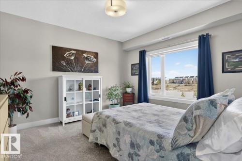 This property features a room with light-colored walls and grey carpet - 214 528 Griesbach Parade Parade, Edmonton, AB - Indoor Photo Showing Bedroom