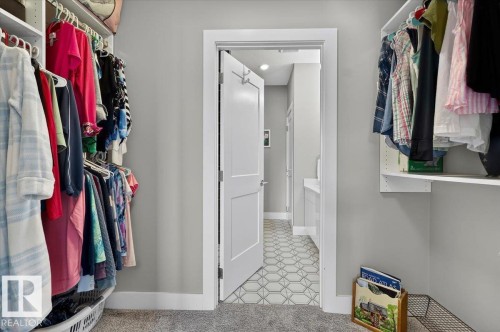 This walk-in closet provides built-in shelving and hanging storage, complemented by soft carpeting - 214 528 Griesbach Parade Parade, Edmonton, AB - Indoor With Storage
