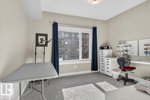 This room features neutral-toned walls, grey carpet, and a window with dark blue curtains - 214 528 Griesbach Parade Parade, Edmonton, AB - Indoor Photo Showing Office