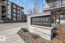 The property features a prominent entrance sign with a stone base, set against a backdrop of modern multi-story buildings with balconies - 214 528 Griesbach Parade Parade, Edmonton, AB  - Outdoor With Balcony 
