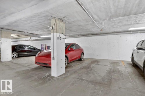 Dedicated parking space within a concrete structure, featuring overhead lighting and visible support columns - 214 528 Griesbach Parade Parade, Edmonton, AB - Indoor Photo Showing Garage