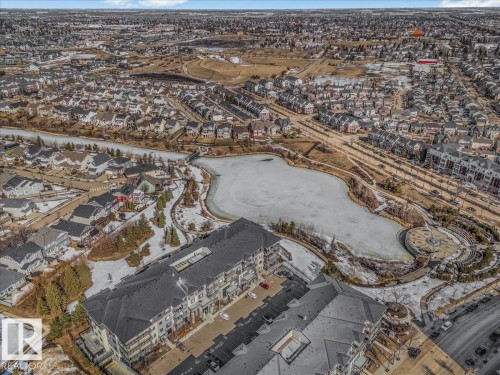 This property offers an aerial view of a residential area, including a large building with a dark roof and balconies - 214 528 Griesbach Parade Parade, Edmonton, AB - Outdoor With View