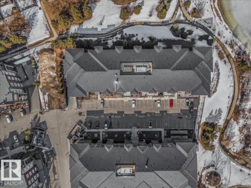 The property features a large building with a dark grey roof, surrounded by paved parking areas - 214 528 Griesbach Parade Parade, Edmonton, AB - Outdoor With View