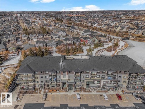 The property features a multi-story building with a dark-colored roof and balconies, overlooking a developed residential area - 214 528 Griesbach Parade Parade, Edmonton, AB - Outdoor With View