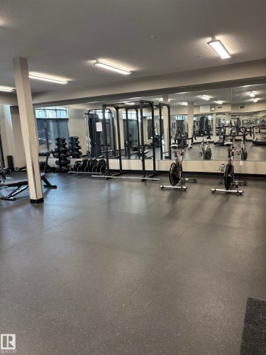This well-equipped fitness area features a variety of exercise machines, free weights, and mirrored walls - 214 528 Griesbach Parade Parade, Edmonton, AB - Indoor Photo Showing Gym Room