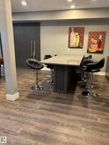 This space features recessed lighting, hardwood flooring, and a contemporary bar-height table with seating - 214 528 Griesbach Parade Parade, Edmonton, AB - Indoor