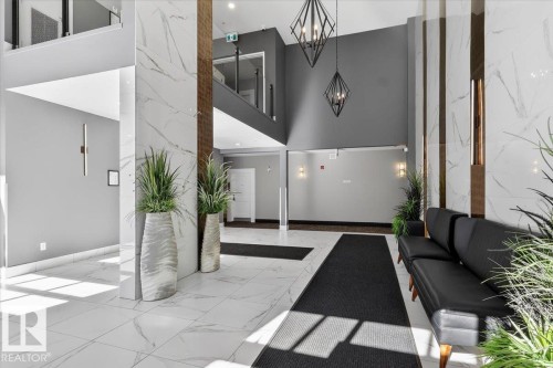 The property features a stylish lobby with white marble-look tile flooring and accent walls - 214 528 Griesbach Parade Parade, Edmonton, AB - Indoor Photo Showing Other Room