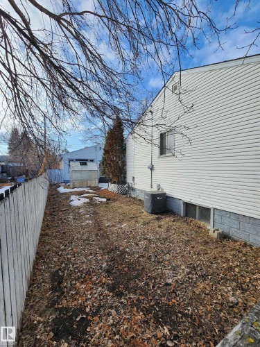 The property features a spacious yard with a white wooden fence and a visible side exterior wall with vinyl siding - 10305 98 Avenue, Fort Saskatchewan, AB - Outdoor
