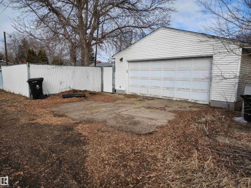 Detached garage with white siding and a white garage door, featuring a concrete pad directly in front - 10305 98 Avenue, Fort Saskatchewan, AB - Outdoor