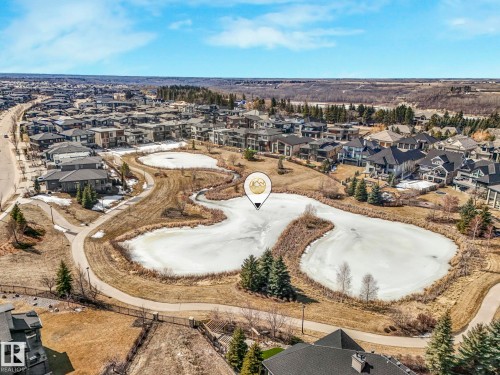 Aerial view showcasing the surrounding neighborhood with residential properties, a winding pathway, and a frozen pond - 2794 Wheaton Drive, Edmonton, AB 